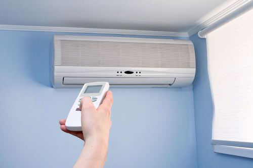 Homeowner using remote to control ductless AC