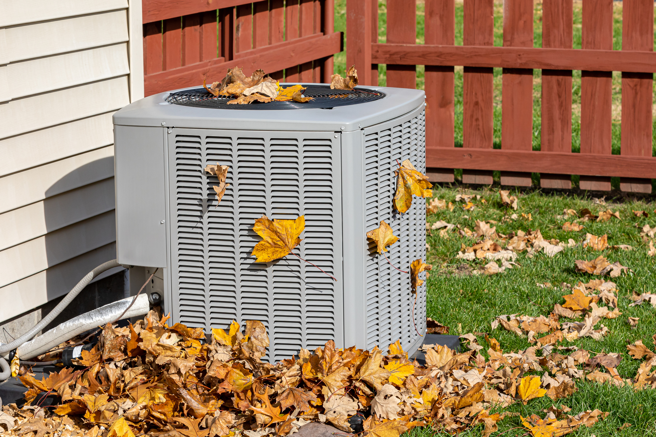AC condenser unit with fall leaves on and around it