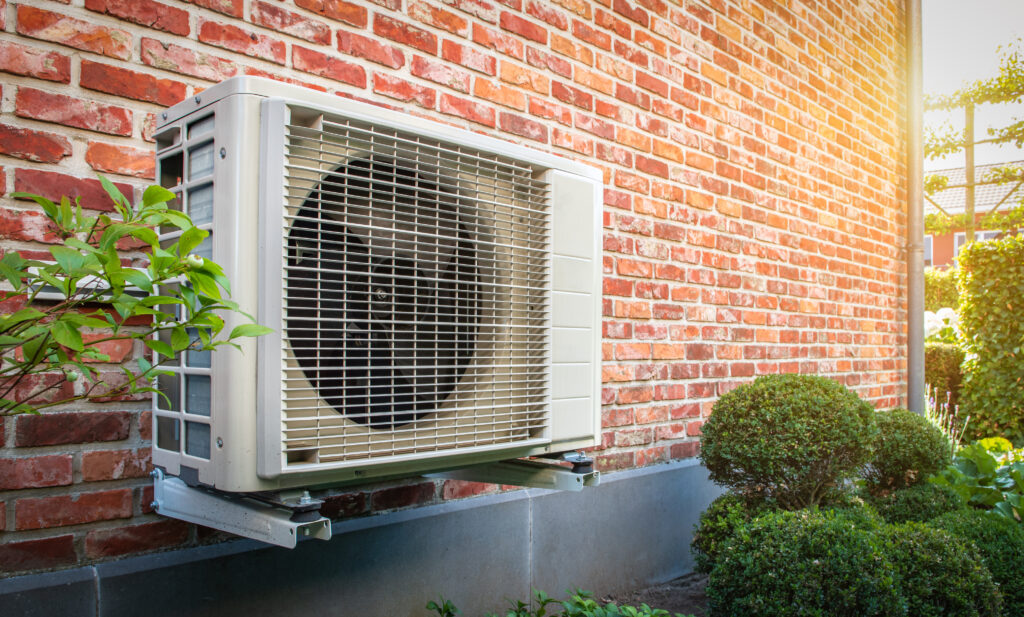 Mounted heat pump unit against brick wall