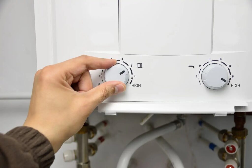 Person turning knob to adjust temperature setting on tankless water heater