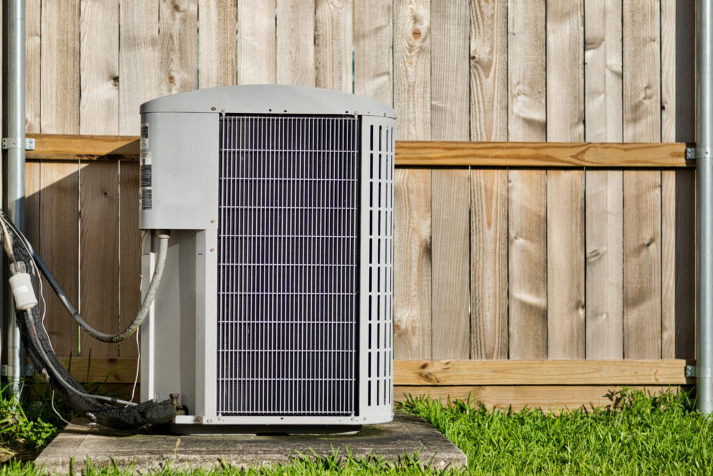 Brand new AC condenser unit in front of wooden fence