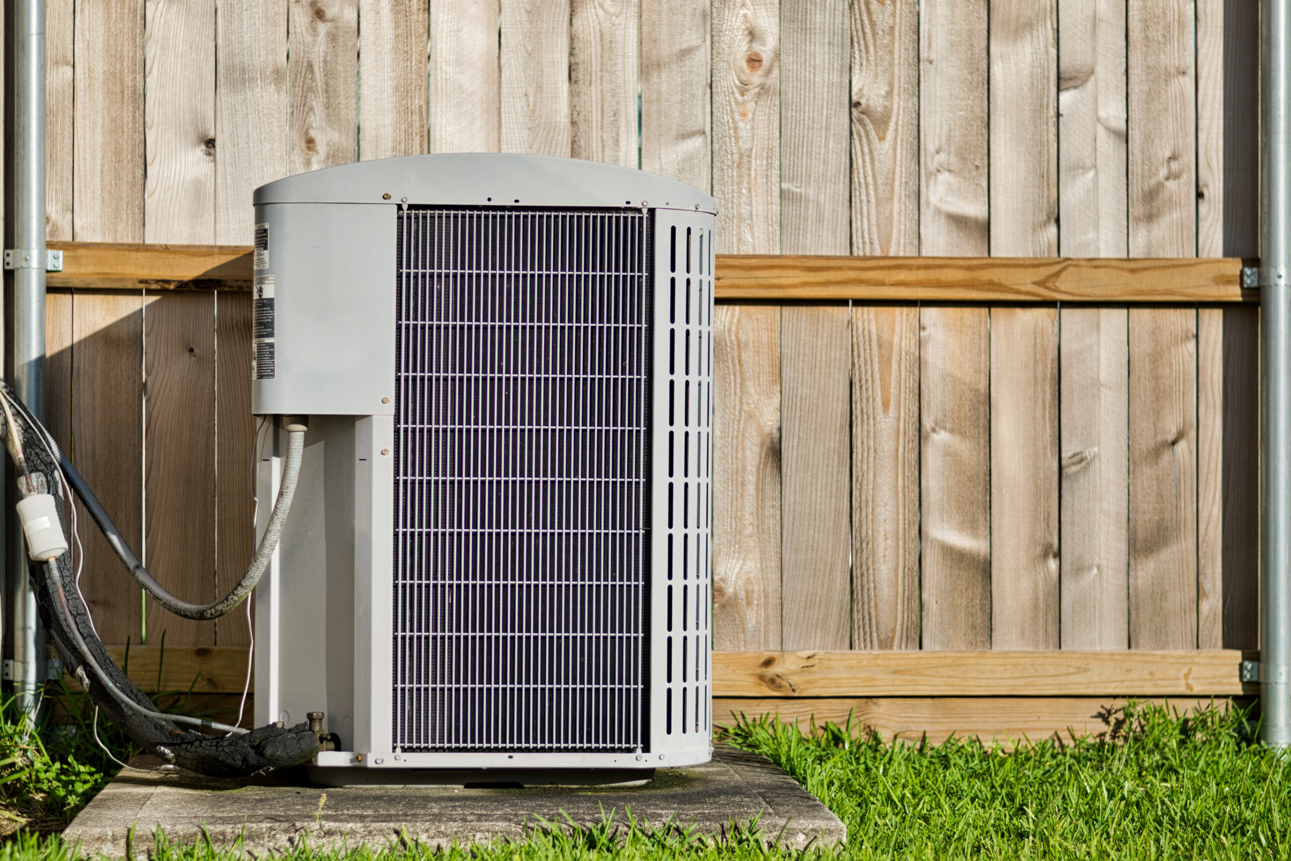 Brand new AC condenser unit in front of wooden fence